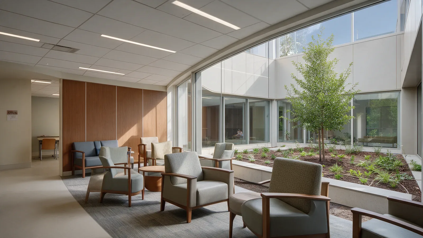 Sala para familiares en un centro sanitario, junto a un jardín, con luz lineal empotrada.